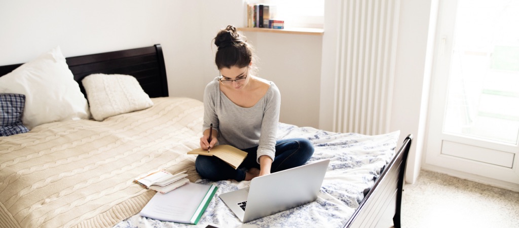 Woman working from home on her bed